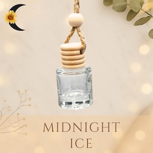 May include: A clear glass car air freshener bottle with a wooden cap and a hanging rope. The bottle is square-shaped and has the words "MIDNIGHT ICE" printed on the bottom. The background is a soft beige color.
