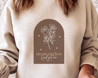Puede incluir: Una sudadera beige con un diseño de arco marrón que presenta una ilustración floral blanca y el texto "no worries God got me".