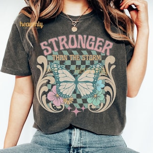 Más fuerte que la tormenta PNG Diseño de sublimación cristiano vintage, Camiseta de Jesús con mariposa y fe PNG, Versículo bíblico religioso retro a cuadros PNG