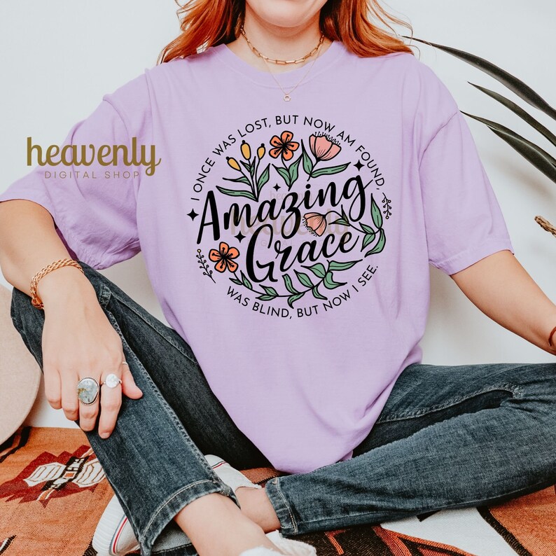 May include: A purple t-shirt with a floral design and the text "I once was lost, but now am found. Amazing Grace was blind, but now I see."