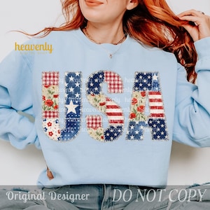 Puede incluir: Sudadera azul claro con la palabra "USA" en un diseño de patchwork. Las letras presentan patrones de la bandera estadounidense, estampados florales y estrellas. El texto "heavenly" está encima de la palabra "USA". Las palabras "Original Designer" y "DO NOT COPY" están en la parte inferior.