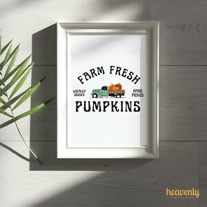 May include: A framed print featuring the text "Farm Fresh Pumpkins" in black. A teal truck illustration carries pumpkins. The words "Locally Grown" and "Hand Picked" are also included. The print is in a white frame.