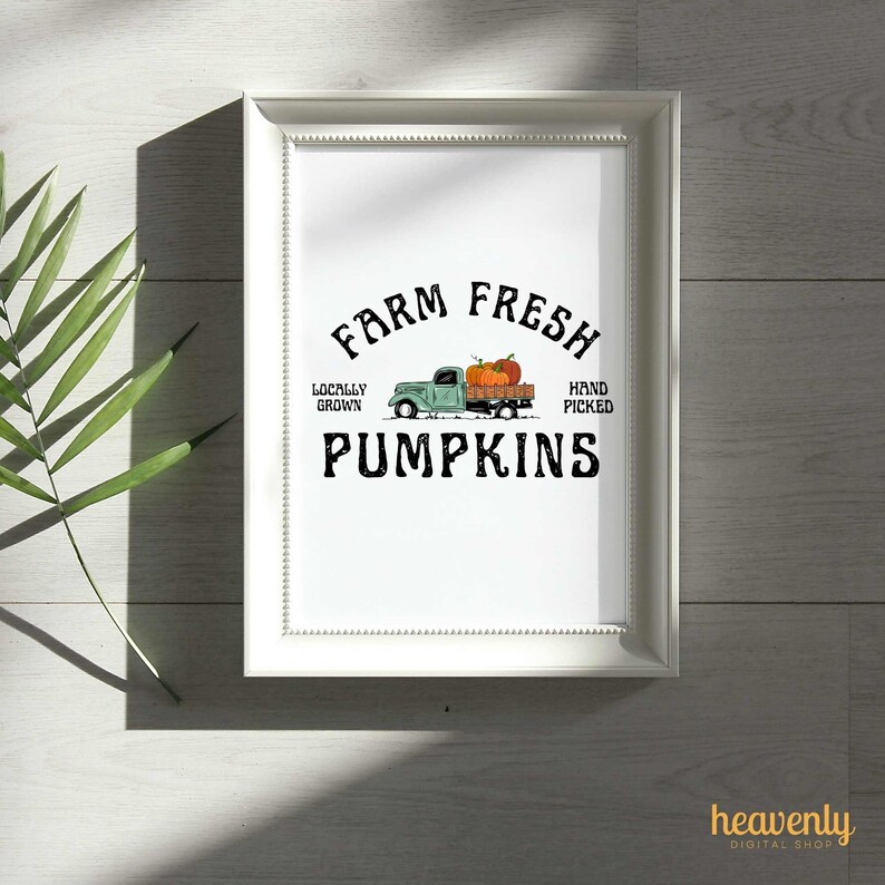 May include: A framed print featuring the text "Farm Fresh Pumpkins" in black. A teal truck illustration carries pumpkins. The words "Locally Grown" and "Hand Picked" are also included. The print is in a white frame.