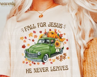 May include: A white t-shirt with a green vintage truck carrying pumpkins and fall leaves. The text "FALL FOR JESUS = HE NEVER LEAVES" is printed on the shirt.