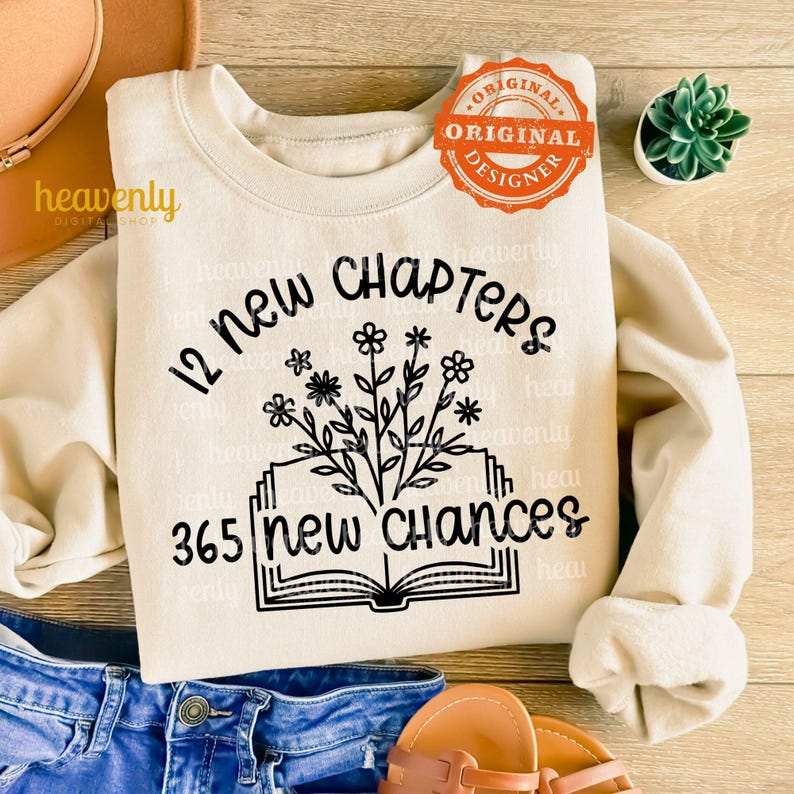 May include: A beige sweatshirt with a black graphic design of a book with flowers and the text "12 new chapters 365 new chances".