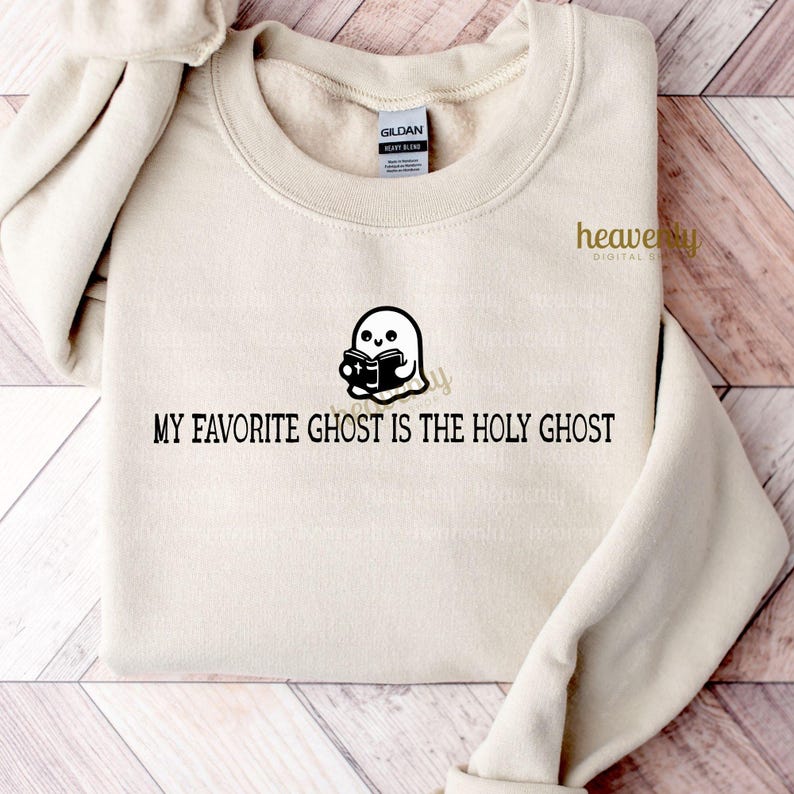 K&ouml;nnte beinhalten: Ein beiger Pullover mit dem Text "My Favorite Ghost is the Holy Ghost" und einem Comic-Geist, der ein Buch h&auml;lt.