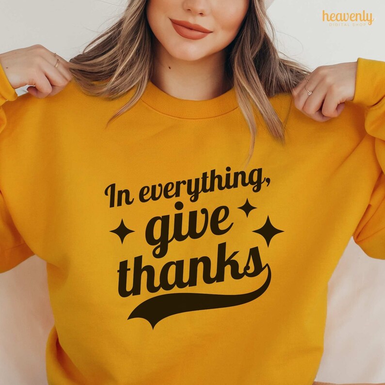 May include: A yellow sweatshirt with the text "In everything, give thanks" in a retro font with black stars on either side of the word "give".