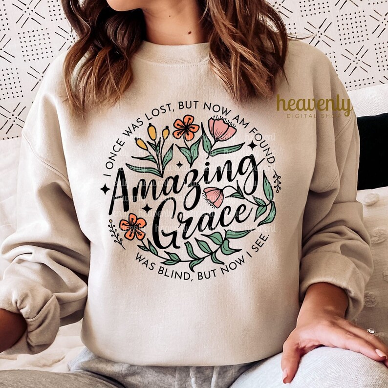 May include: A beige sweatshirt with a floral design and the text "I once was lost, but now am found. Amazing Grace. Was blind, but now I see."