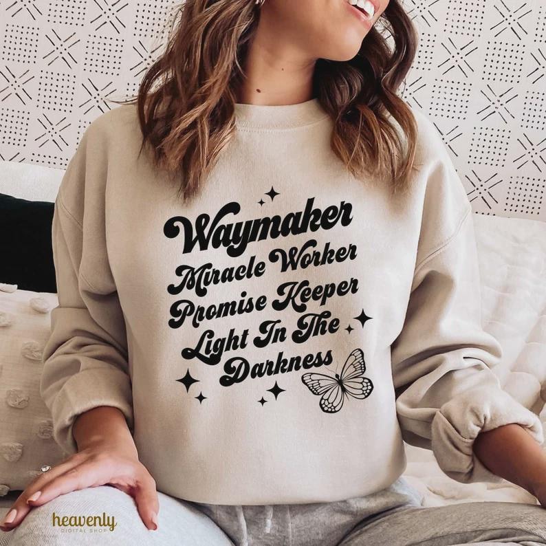 Pu&ograve; includere: Una felpa beige con le parole "Waymaker, Miracle Worker, Promise Keeper, Light In The Darkness" in nero. Sono presenti anche una farfalla e delle stelle. La felpa &egrave; uno stile comodo e casual.