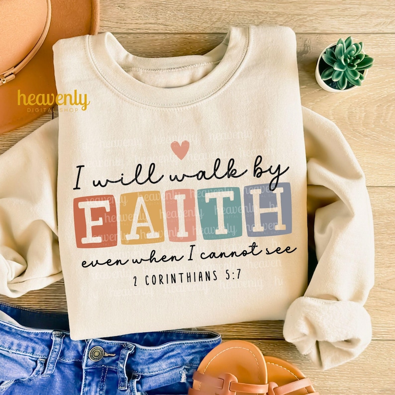 May include: A beige sweatshirt with a colorful graphic that says "I will walk by FAITH even when I cannot see 2 Corinthians 5:7".