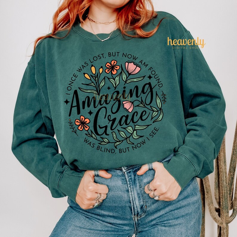 May include: A teal green sweatshirt with a floral design and the text "I once was lost, but now am found. Amazing Grace. Was blind, but now I see."