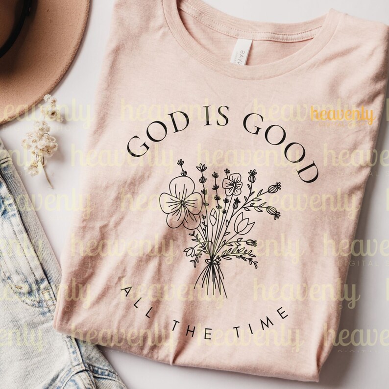 Peut inclure: Un t-shirt rose avec un motif floral noir et le texte "God is Good All the Time".