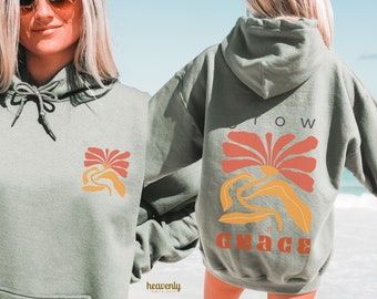 Puede incluir: Una sudadera con capucha verde salvia con un gráfico de flores y el texto "Grow in Grace" en la espalda. La flor es naranja y roja.