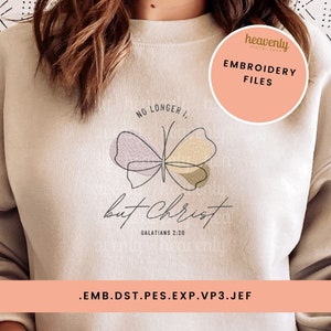 May include: A beige sweatshirt with a butterfly graphic and the text "No Longer I, But Christ, Galatians 2:20". The text "Embroidery Files" is in a circle with a pink background. The text ".emb.dst.pes.exp.vp3.jef" is at the bottom of the image.