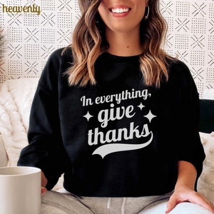 May include: Black sweatshirt with the text "In everything, give thanks" in white lettering with a white star on each side of the word "give".
