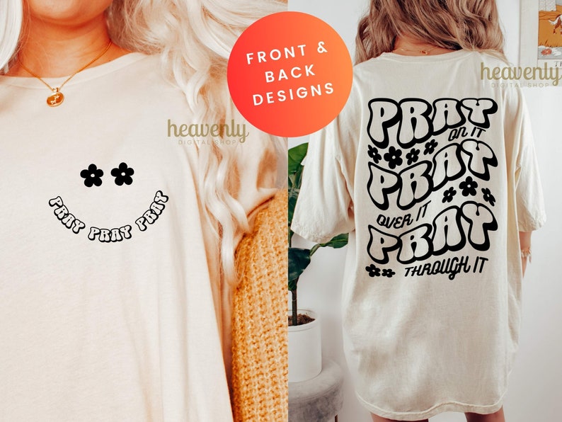 May include: Cream-colored t-shirt with a smiley face design featuring black daisy-shaped eyes and the words "PRAY PRAY PRAY" in a curved font. The back of the shirt has the words "PRAY ON IT, PRAY OVER IT, PRAY THROUGH IT".