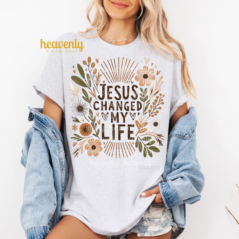 May include: A gray t-shirt with a floral design and the text "Jesus Changed My Life" in brown lettering.