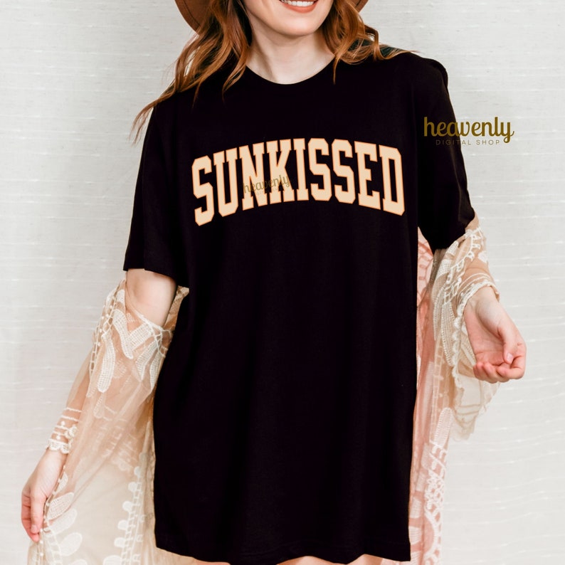 May include: A black t-shirt with the word "SUNKISSED" printed in a large, yellow font.