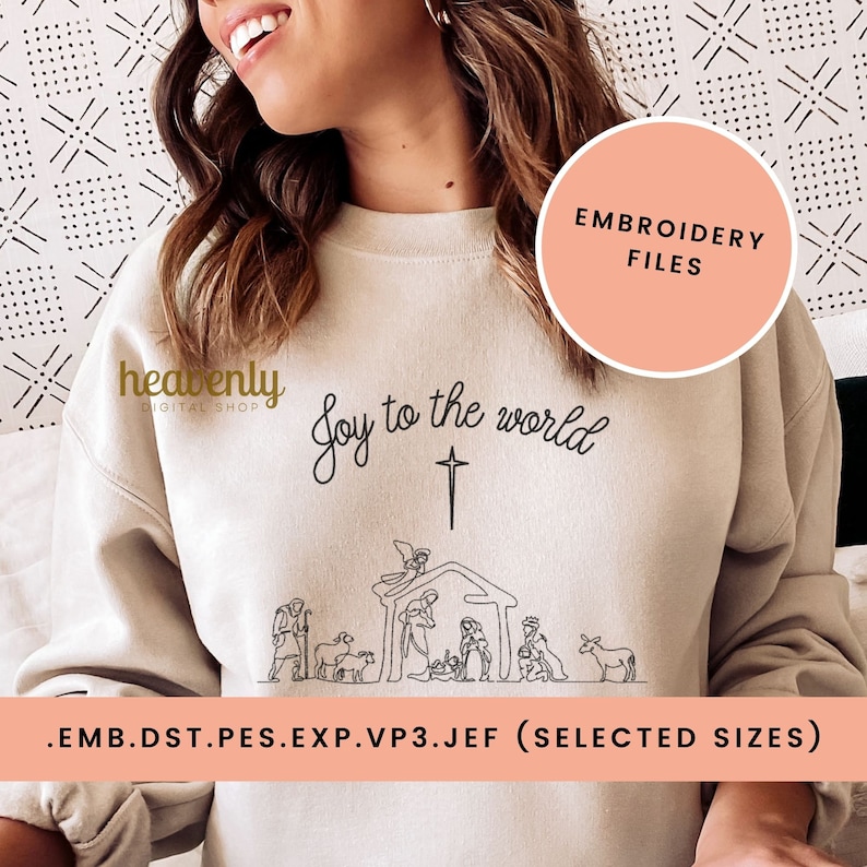 K&ouml;nnte beinhalten: Ein beiger Pullover mit einer schwarzen Linienzeichnung der Weihnachtsgeschichte und dem Text "Joy to the world". Der Text "heavenly digital shop" befindet sich ebenfalls auf dem Pullover. Der Pullover wird von einer Person getragen. Der Text ".emb.dst.pes.exp.vp3.jef (selected sizes)" befindet sich am unteren Rand des Bildes.