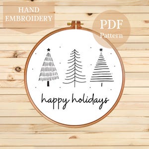 May include: A hand-embroidered Christmas tree design in a wooden embroidery hoop. The design features three stylized black trees with a star or asterisk at the top, and the words "happy holidays" in cursive. The words "Hand Embroidery" and "PDF Pattern" are also visible.