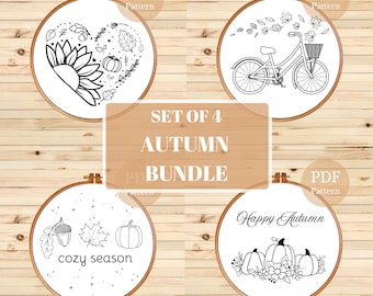 Puede incluir: Conjunto de cuatro patrones de bordado en blanco y negro con temática otoñal. Los patrones incluyen un girasol, una bicicleta con hojas, una calabaza y una bellota, y una calabaza con flores y el texto "Happy Autumn".