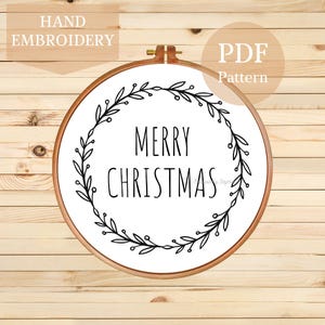 May include: A round wooden embroidery hoop containing white fabric with a black line art design of a circular wreath of leaves and berries surrounding the text MERRY CHRISTMAS. The image includes the text HAND EMBROIDERY and PDF Pattern.
