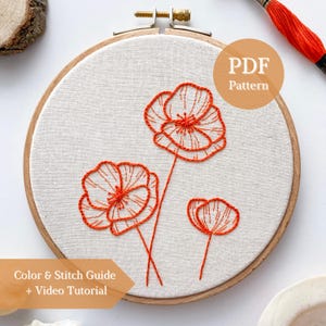 May include: An embroidery hoop containing light-coloured fabric with three hand-stitched orange poppy flowers. The design features detailed line work for the petals and centres. A circular badge on the image reads PDF Pattern and Colour & Stitch Guide + Video Tutorial.
