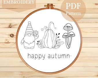 Puede incluir: Un bastidor de bordado de madera con un dibujo lineal en blanco y negro de un gnomo, una calabaza y setas. El texto "happy autumn" está debajo de las imágenes. También se ven las palabras "HAND EMBROIDERY" y "PDF Pattern".