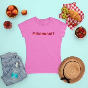 May include: Pink women's t-shirt with the word "MISANDRIST" printed in red on the front.