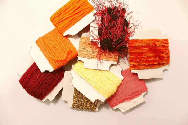 K&ouml;nnte beinhalten: Sortiment an bunten Stickgarnrollen in verschiedenen Oranget&ouml;nen, Rot- und Gelbt&ouml;nen. Das Garn ist auf wei&szlig;en Papprollen aufgewickelt.