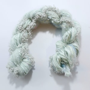 May include: A light green yarn with white and blue accents. The yarn is twisted and has a fluffy texture.
