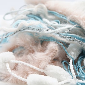 Peut inclure: Un tas de fil doux et moelleux dans des tons de blanc, bleu clair et beige. Le fil est emmêlé et noué, créant un visuel texturé et intéressant.