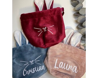 May include: Three velvet Easter bunny bags in different colors. The bags have bunny ears and a white embroidered face. The bags are labeled "Christian", "Laura", and one is unlabeled.