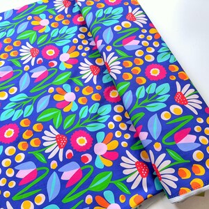Könnte beinhalten: Eine Stoffrolle mit einem lebendigen Blumenmuster. Das Design zeigt bunte Blumen in Rosa, Weiß, Gelb und Orange, vor einem tiefblauen Hintergrund. Grüne Blätter und Stiele vervollständigen das botanische Thema.