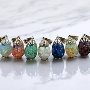 May include: Seven silver pendant necklaces with iridescent opal-like stones in various colors, including white, pink, green, blue, and purple.