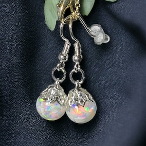 May include: A pair of silver earrings with iridescent white opal stones set in a delicate filigree design.