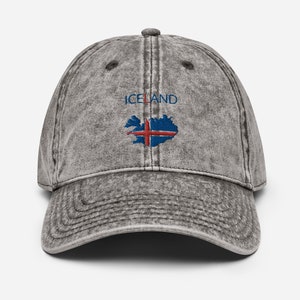 May include: A gray vintage washed cotton baseball cap with the word "ICELAND" embroidered in blue and red on the front. The cap features an embroidered outline of Iceland with the Icelandic flag inside.