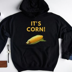 May include: Black hooded sweatshirt with the text "IT'S CORN!" in yellow letters and a cartoon image of an ear of corn.