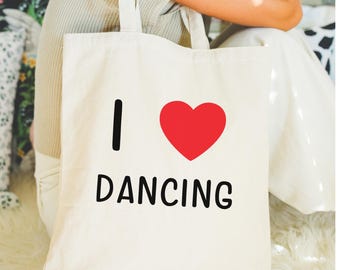 May include: White canvas tote bag with black text that says "I love dancing" and a red heart.