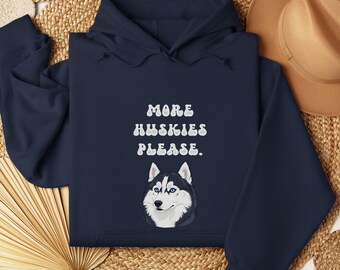 May include: Navy blue hoodie with the text "MORE HUSKIES PLEASE." and a graphic of a husky dog with blue eyes. The hoodie is made of a soft material and has a hood and long sleeves.