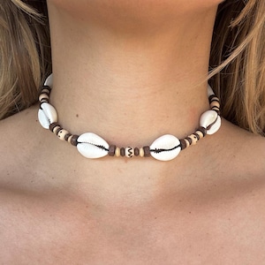 Può includere: Una collana choker con conchiglie bianche e perline di legno marrone.