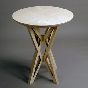 May include: A light wood side table with a round top and a unique, geometric, X-shaped base.