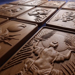May include: A set of wooden plaques with various carvings, including a scorpion, a coconut, a lion, a person holding a bowl, and a palm tree. The plaques are all made of a light brown wood and have a smooth, polished finish.