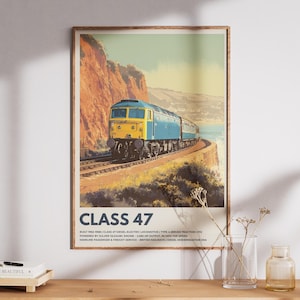Puede incluir: Un póster vintage enmarcado con una locomotora diésel Clase 47. El tren azul y amarillo viaja por una vía férrea costera. El póster tiene un marco marrón y se exhibe sobre una superficie de madera.