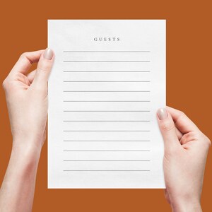 May include: A white sheet of paper with lined paper and the word "GUESTS" at the top. Two hands are holding the paper.