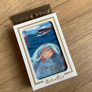 May include: A deck of playing cards in a white box with gold trim. The card face features a blue ocean scene with a ship and a character with pink hair under a blue blanket. The text includes JOKER, STUDIO GHIBLI, and Japanese characters.