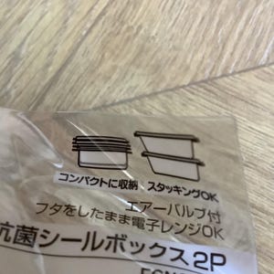 May include: A clear plastic package with Japanese text and illustrations of food storage containers. The text includes phrases like "compact storage" and "microwave safe." The image shows a close-up of the packaging.