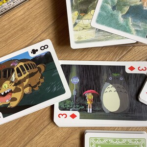 May include: Playing cards featuring illustrations from the animated film "My Neighbor Totoro." The cards show characters like Totoro and the Catbus. The deck includes a Joker card and various suit cards.