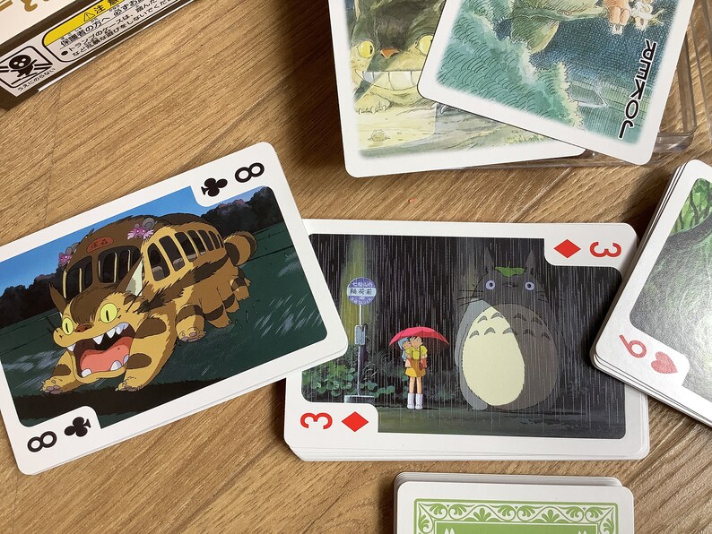 May include: Playing cards featuring illustrations from the animated film "My Neighbor Totoro." The cards show characters like Totoro and the Catbus. The deck includes a Joker card and various suit cards.