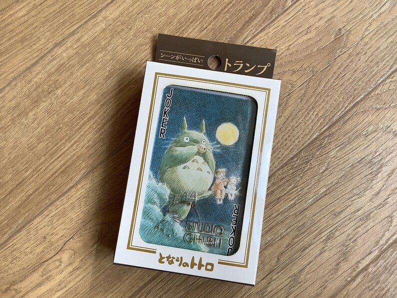 May include: A deck of playing cards featuring a Studio Ghibli illustration of Totoro. The card shows Totoro standing in front of a moon, with the word "Joker" on the side. The packaging has Japanese text.